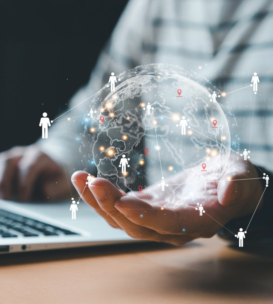 While working with a laptop on their desk, a person holding a hologram of a world image.